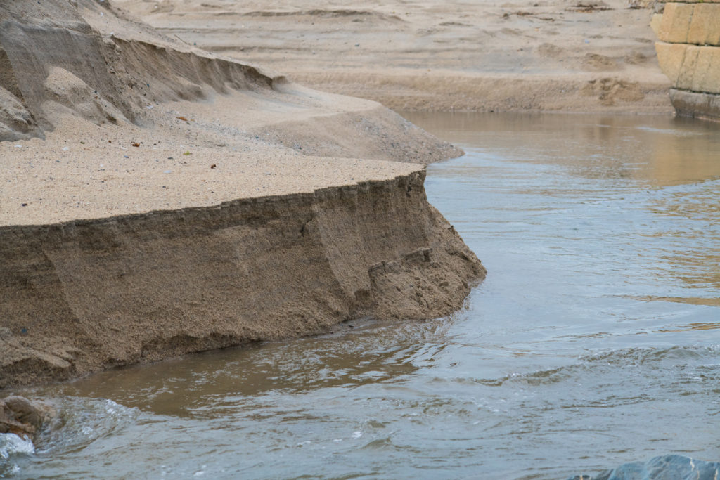 A sandbank on a beach in Cornwall being eroded by the tide